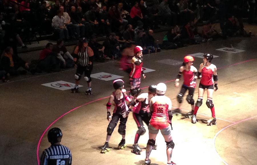 Members from two teams in the Minnesota RollerGirls league, the Rockits and the Dagger Dolls, get ready to block the opposite teams jammers in order to ensure their jammer gets into the lead. 