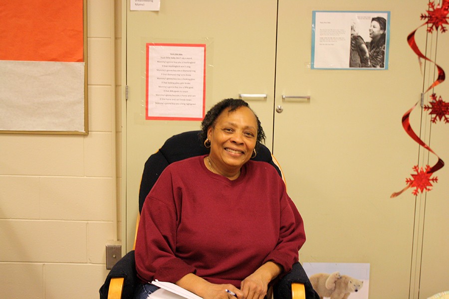 Lead infant teacher Tanya Lovelace pauses during a busy day to sit in a rocking chair in the T.A.P.P.P room. She smiles while watching over the infants playing, sleeping, and greeting their parents at the end of the day.