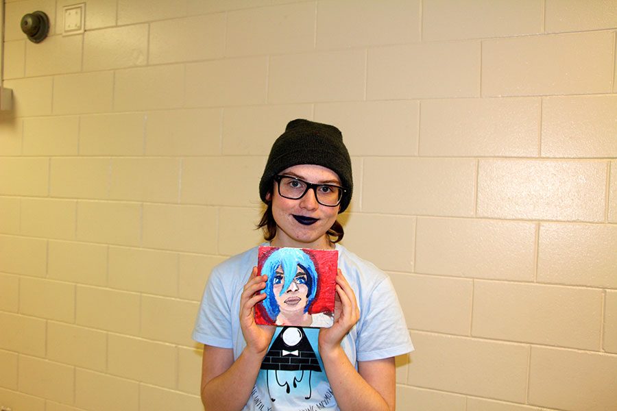 Pictured above is junior Finn Niesewand holding a self portrait painting that encapsulates his identity. “Everything about being a teenage is a process and everything about being a trans teenager is even more, because you are discovering yourself twice as much as everyone else is,” said Niesewand. Photo: Katherine Lundquist