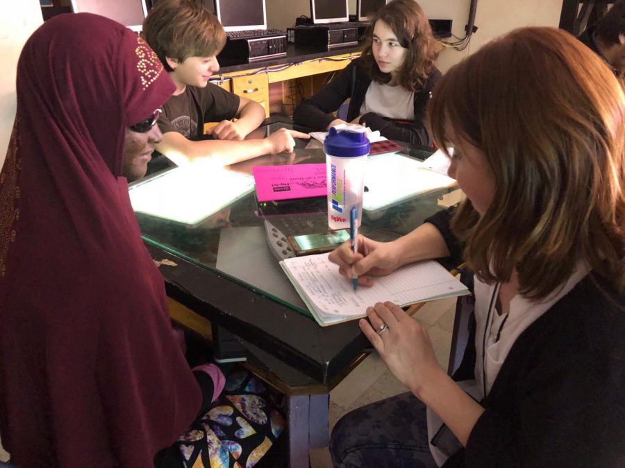 Pictured above freshman Haney Mohamed and her SEA (special education assistant), Laura Anderson with students Sasha Rapacz (left) and Beatrice Kennedy-Logan (right) in the background. In this photo, Anderson copies definitions from the board into Mohamed’s notebook and explains the information that she cannot see. “When teachers write on, lets say a white board: visually impaired people cannot see the whiteboard. The SEA’s explain what is written, they tell them what it says,” said Haney Mohamed. This extra help is vital for a successful schooling experience for students with visual impairments. Picture: Kinsley Wilcox-McBride