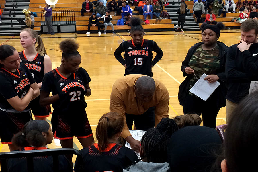 New girls varsity basketball head coach Ricky Hill (middle) draws up a game plan during the December 19th match vs. North High School. “I started coaching my daughter, and thats how I got into coaching girls basketball.”