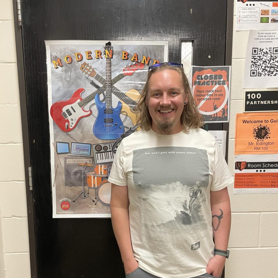Mr. Eddington, guitar and sound production teacher, who proposed the idea for a “Modern Music” program, stands in front of his room, situated behind the front desk.