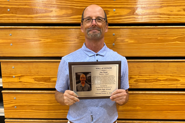 Coach Joe Hyser, a fixture of South’s basketball program and Machine Tech teacher here at South, stands proudly with his newest honor, a spot on South High’s Wall of Fame. Photo courtesy of Caroline Gladbach